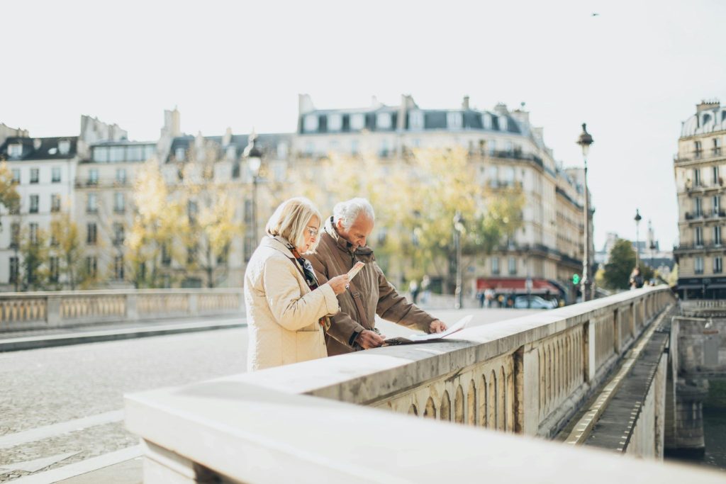 An elderly couple using a map in a scenic European city with historical architecture.