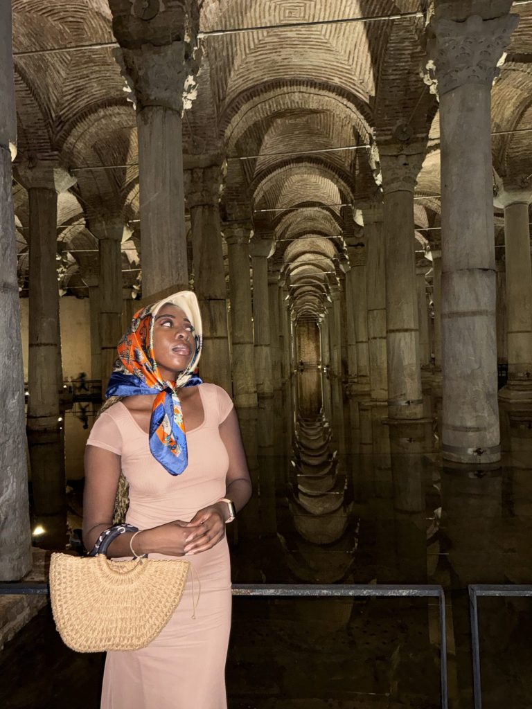 Girl wearing colorful scarf, holding a bag, standing in a cave, and Istanbul Turkey