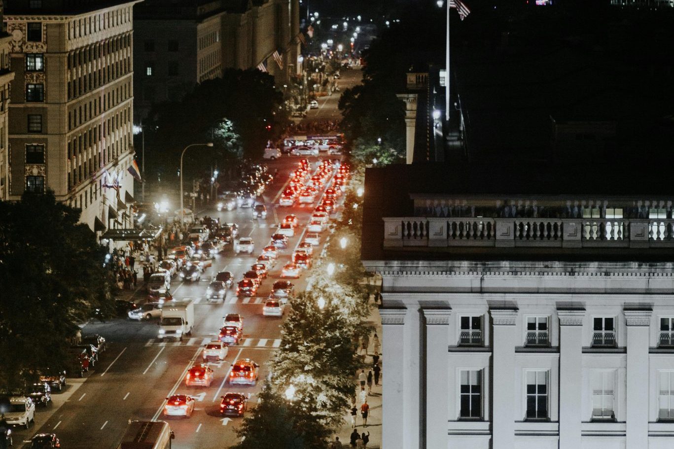 Aerial view of bustling Washington, DC streets at night with vibrant streetlights and traffic.