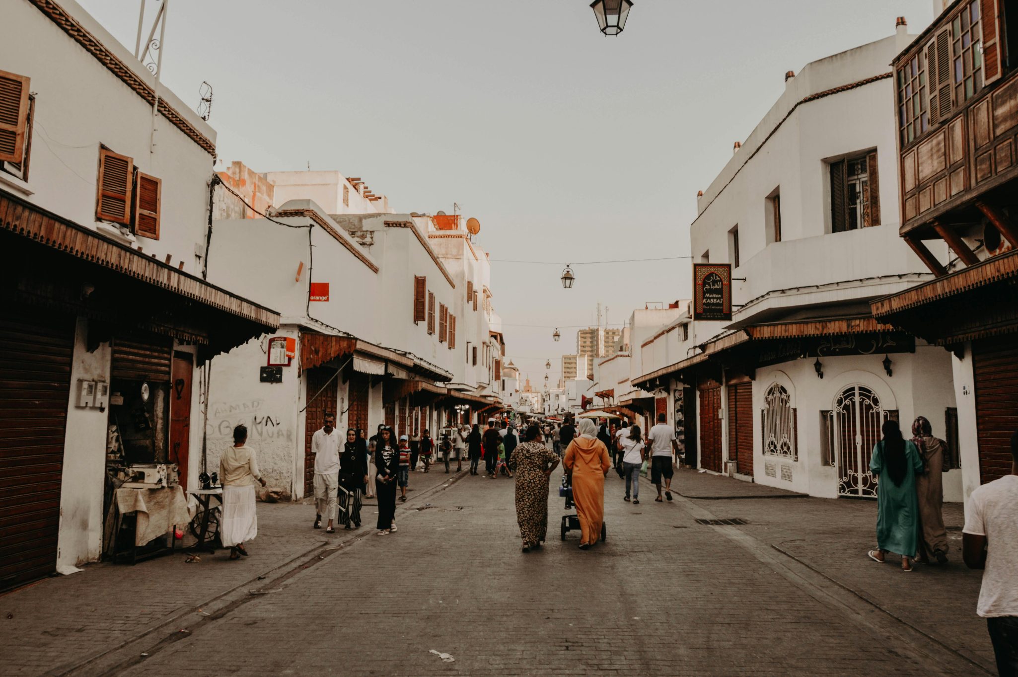 A street in Rabat, Morocco with people walking and shops lining the road.