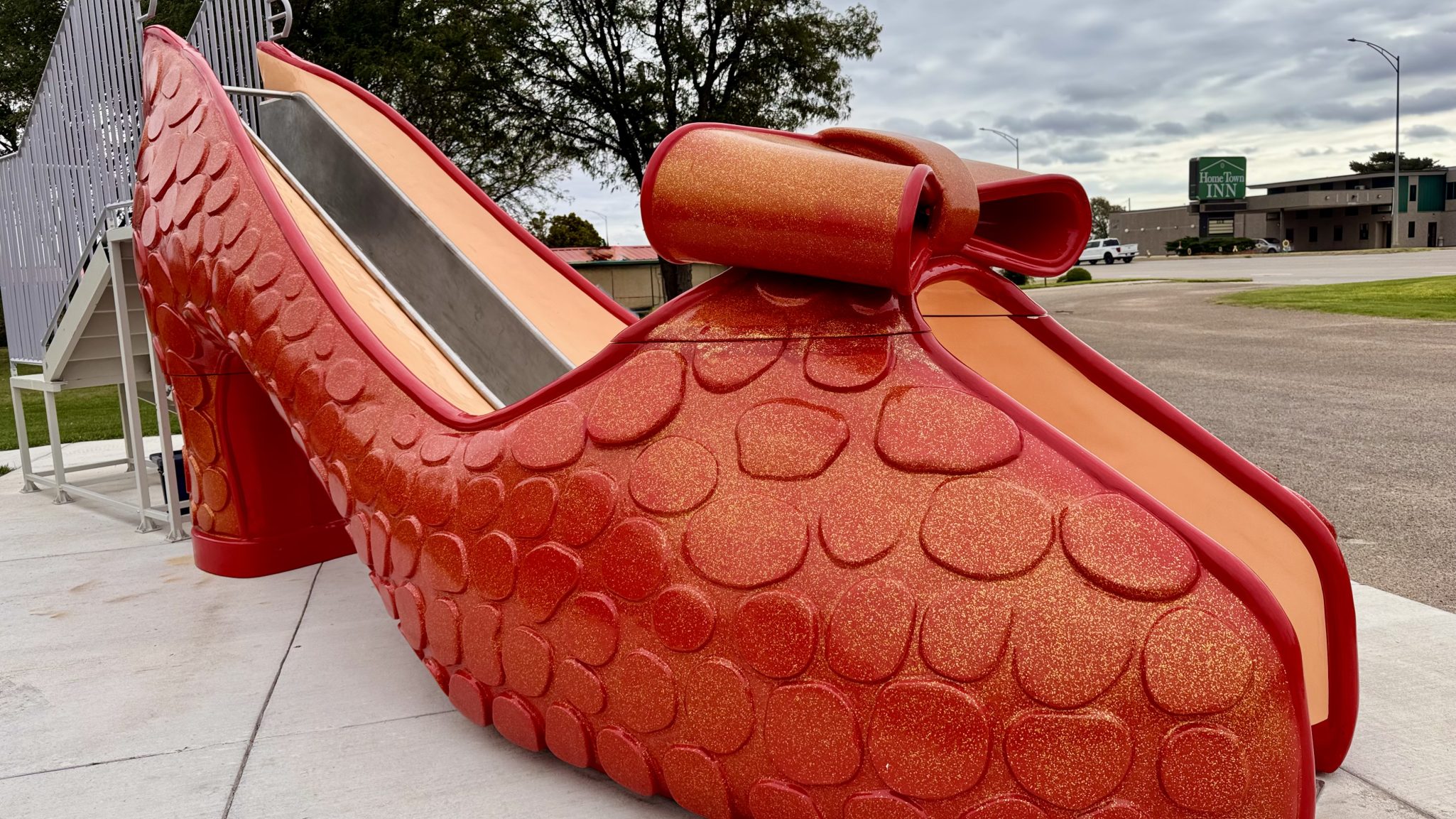 A large, decorative slide shaped like a high-heeled shoe, featuring a glittery red exterior and a smooth slide surface.