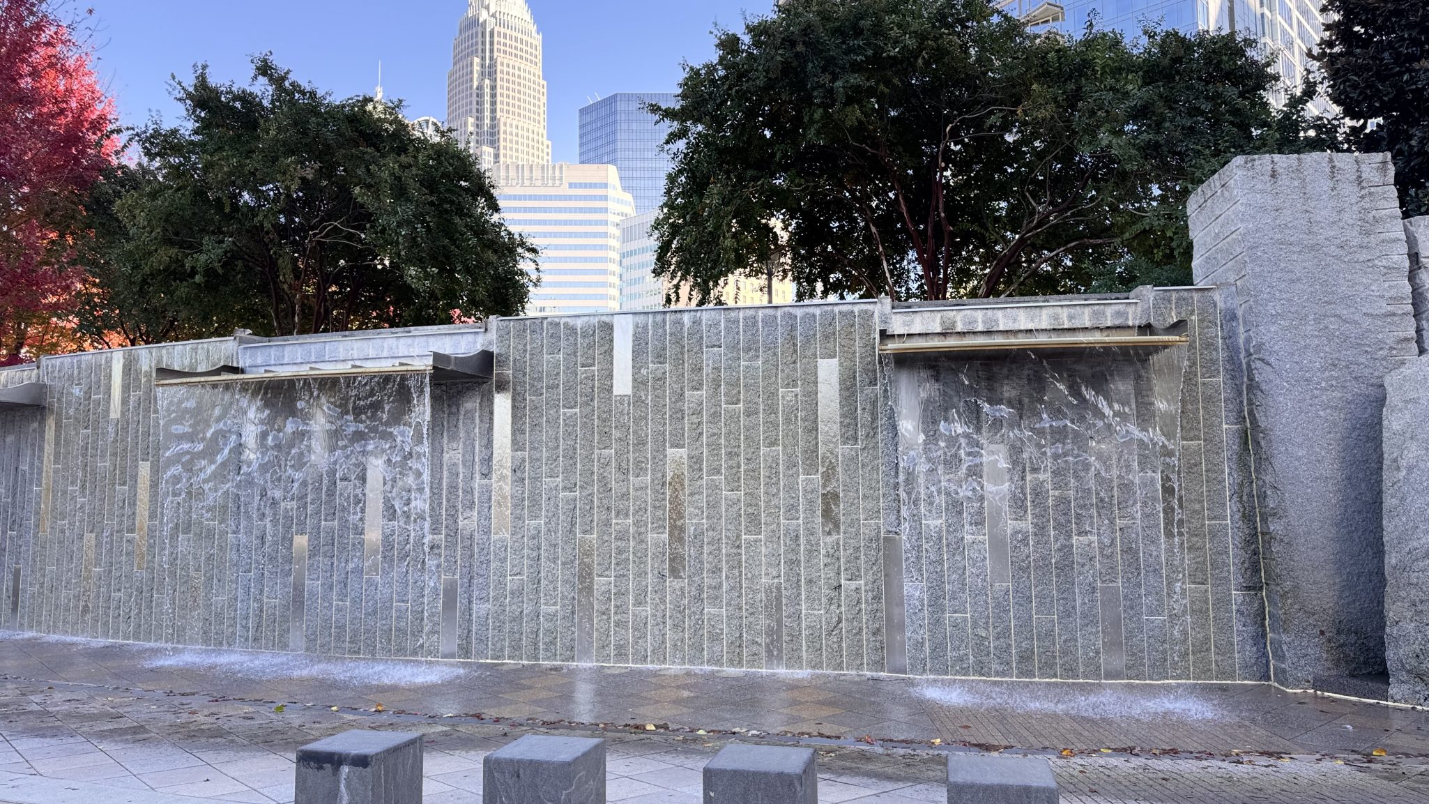 A rusted bear sculpture playing a banjo, surrounded by trees and natural landscaping at Valley Bear Farms.