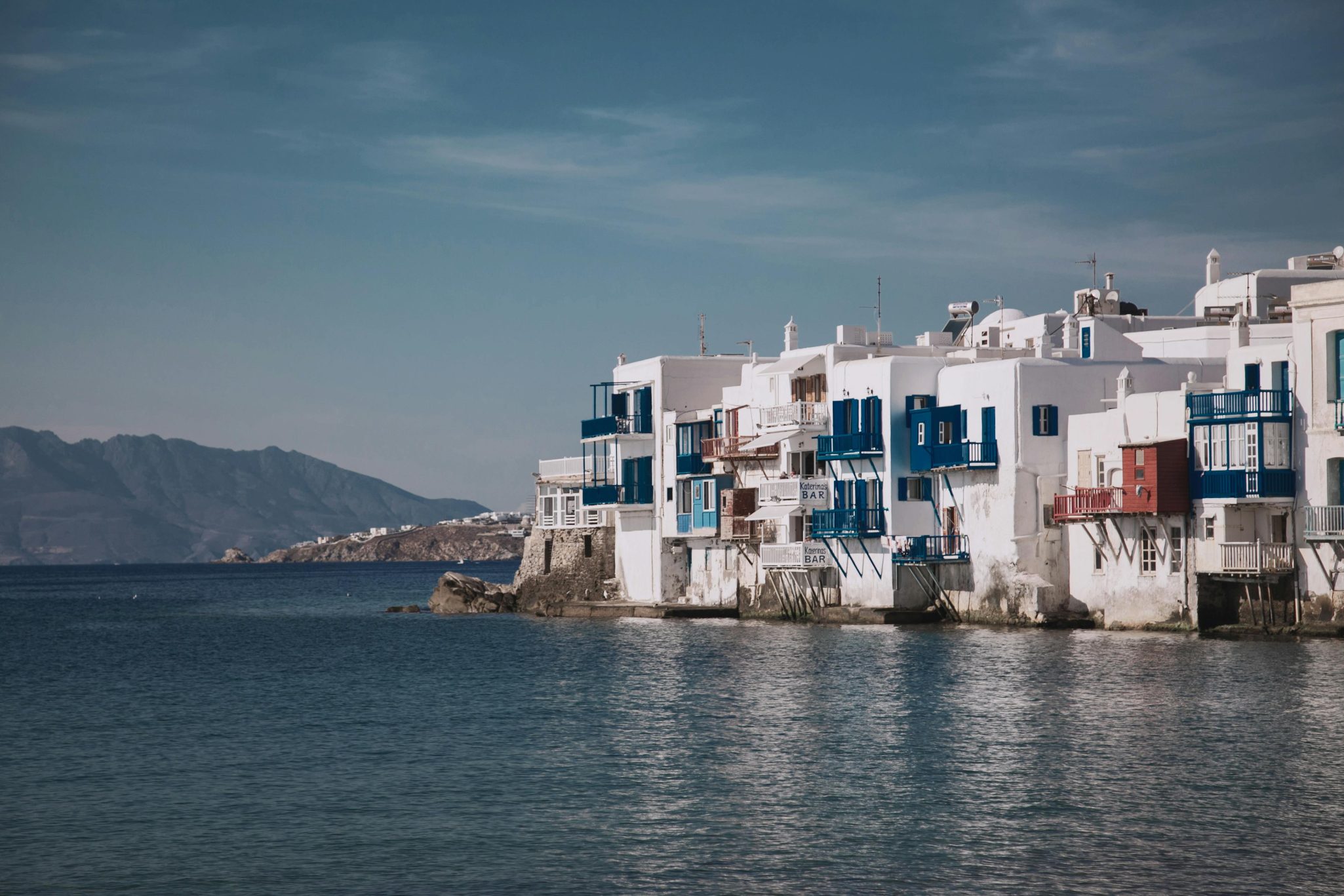 Explore the iconic seaside architecture of Mykonos, Greece with its vibrant blue and white houses perched by the Aegean Sea.